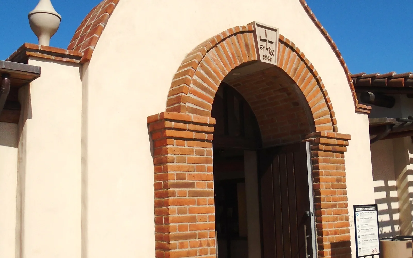 The entrance to Mission San Juan Capistrano with its historic wooden door and brick archway